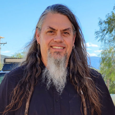 A man with long dark hair and gray beard