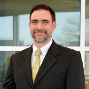 A man with dark hair and wearing a suit.